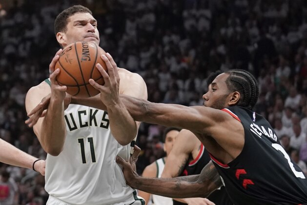 Milwaukee Bucks' Brook Lopez is fouled by Toronto Raptors' Kawhi Leonard during the first half of Game 1 of the NBA Eastern Conference basketball playoff finals Wednesday, May 15, 2019, in Milwaukee. (AP Photo/Morry Gash)
