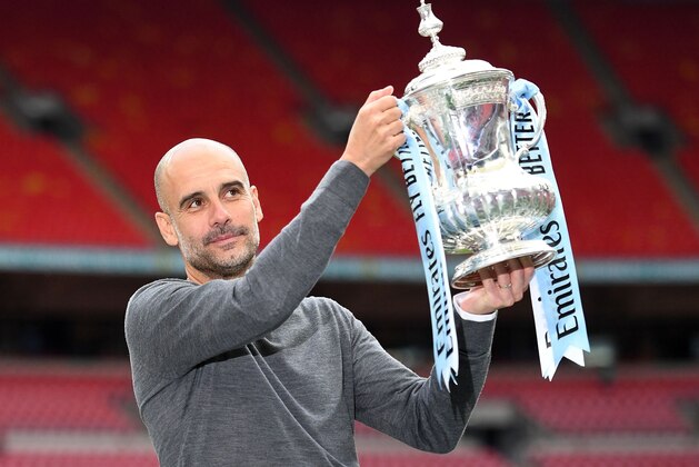 Manchester City's Spanish manager Pep Guardiola holds the winner's trophy as the team celebrates victory after the English FA Cup final football match between Manchester City and Watford at Wembley Stadium in London, on May 18, 2019. - Manchester City beat Watford 6-0 at Wembley to claim the FA Cup. (Photo by Daniel LEAL-OLIVAS / AFP) / NOT FOR MARKETING OR ADVERTISING USE / RESTRICTED TO EDITORIAL USE        (Photo credit should read DANIEL LEAL-OLIVAS/AFP/Getty Images)