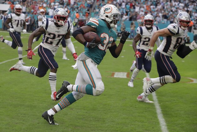 FILE - In this Dec. 9, 2018, file photo, Miami Dolphins running back Kenyan Drake (32) runs for a touchdown during the second half of an NFL football game against the New England Patriots, in Miami Gardens, Fla. “I mean honestly, I'm sitting before you all and I still don't believe it,