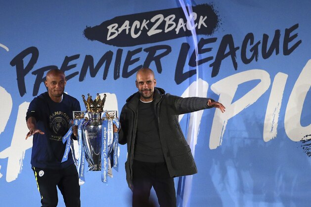 Manchester City coach Pep Guardiola, right, and captain Vincent Kompany hold the trophy as they celebrate with their supporters at the Etihad Stadium in Manchester, England, Sunday May 12, 2019 the day they won the English Premier League title. Manchester City retained the Premier League trophy after coming from behind to beat Brighton 4-1 and see off Liverpool's relentless challenge on the final day of the season on Sunday. (AP Photo/Jon Super)