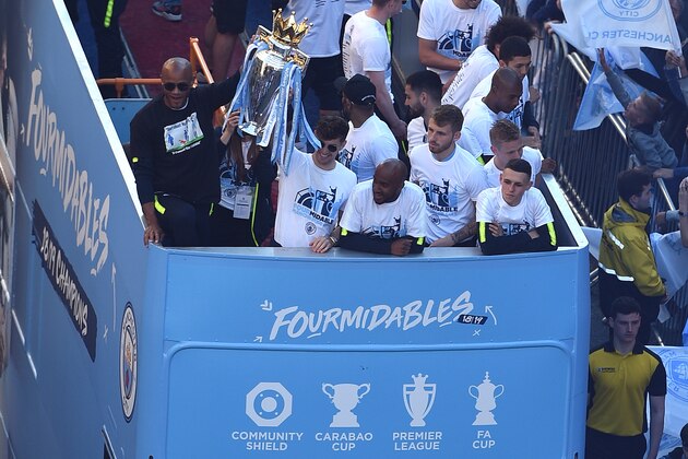 Manchester City's Belgian defender Vincent Kompany and Manchester City's English defender John Stones hold up the Premier League trophy to the team's fans as they take part in an open-top bus parade through Manchester, northern England on May 20, 2019, to celebrate winning the 2019 Premier League title, the FA Cup and English League Cup. - Pep Guardiola saluted Manchester City's history makers after they clinched the domestic treble with a swaggering 6-0 rout of Watford in the FA Cup final on Saturday. Just a week after winning a second successive Premier League crown, City's record-equalling FA Cup final victory made them the first English club to win the English title, FA Cup and League Cup in the same season. (Photo by Oli SCARFF / AFP)        (Photo credit should read OLI SCARFF/AFP/Getty Images)
