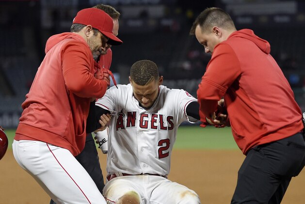 Los Angeles Angels' Andrelton Simmons, center, is helped up by manager Brad Ausmus, left, and a trainer after he was injured while being thrown out at first during the eighth inning of a baseball game against the Minnesota Twins Monday, May 20, 2019, in Anaheim, Calif. (AP Photo/Mark J. Terrill)