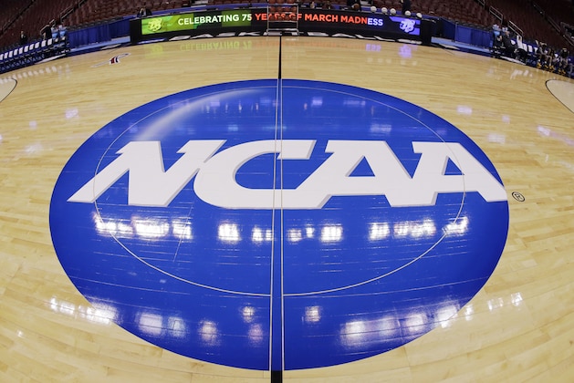 FILE - In this March 21, 2013, file photo taken with a fisheye lens, the NCAA logo is displayed at mid-court before Albany's practice for a second-round game of the NCAA college basketball tournament in Philadelphia. A judge has ruled against the NCAA in a federal antitrust lawsuit, saying football and basketball players should be permitted to receive more compensation from schools but only if the benefits are tied to education. (AP Photo/Matt Slocum, File) FILE - In this March 21, 2013, file photo taken with a fisheye lens, the NCAA logo is displayed at mid-court before Albany's practice for a second-round game of the NCAA college basketball tournament in Philadelphia. A judge has ruled against the NCAA in a federal antitrust lawsuit, saying football and basketball players should be permitted to receive more compensation from schools but only if the benefits are tied to education. (AP Photo/Matt Slocum, File)