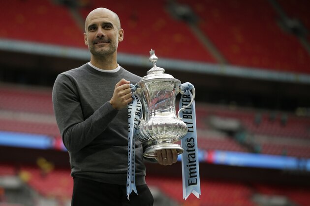 Manchester City's manager Pep Guardiola poses for a picture as lifts the trophy after winning the English FA Cup Final soccer match between Manchester City and Watford at Wembley stadium in London, Saturday, May 18, 2019. Manchester City won 6-0. (AP Photo/Tim Ireland)