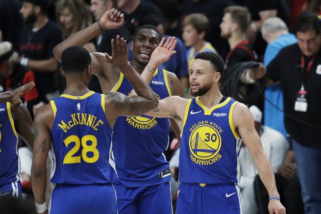 Golden State Warriors guard Stephen Curry, right, greets Alfonzo McKinnie (28) and Kevon Looney, center, during the second half of Game 3 of the team's NBA basketball playoffs Western Conference finals against the Portland Trail Blazers, Saturday, May 18, 2019, in Portland, Ore. The Warriors won 110-99. (AP Photo/Ted S. Warren)