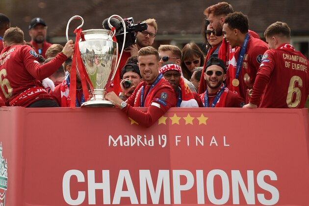 Liverpool's English midfielder Jordan Henderson (C) holds the European Champion Clubs' Cup trophy during an open-top bus parade around Liverpool, north-west England on June 2, 2019, after winning the UEFA Champions League final football match between Liverpool and Tottenham. - Liverpool's celebrations stretched long into the night after they became six-time European champions with goals from Mohamed Salah and Divock Origi to beat Tottenham -- and the party was set to move to England on Sunday where tens of thousands of fans awaited the team's return. The 2-0 win in the sweltering Metropolitano Stadium delivered a first trophy in seven years for Liverpool, and -- finally -- a first win in seven finals for coach Jurgen Klopp. (Photo by Oli SCARFF / AFP)        (Photo credit should read OLI SCARFF/AFP/Getty Images)