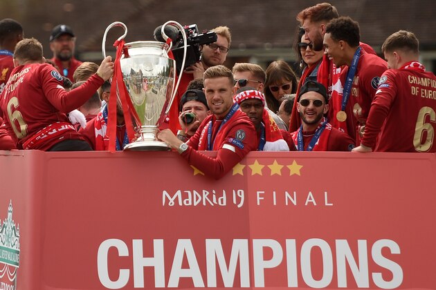 Liverpool's English midfielder Jordan Henderson (C) holds the European Champion Clubs' Cup trophy during an open-top bus parade around Liverpool, north-west England on June 2, 2019, after winning the UEFA Champions League final football match between Liverpool and Tottenham. - Liverpool's celebrations stretched long into the night after they became six-time European champions with goals from Mohamed Salah and Divock Origi to beat Tottenham -- and the party was set to move to England on Sunday where tens of thousands of fans awaited the team's return. The 2-0 win in the sweltering Metropolitano Stadium delivered a first trophy in seven years for Liverpool, and -- finally -- a first win in seven finals for coach Jurgen Klopp. (Photo by Oli SCARFF / AFP)        (Photo credit should read OLI SCARFF/AFP/Getty Images)