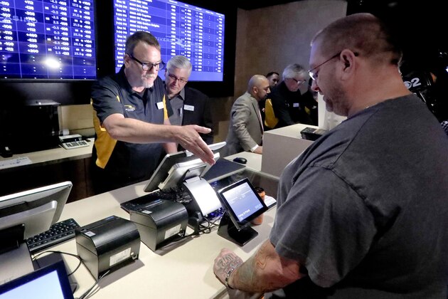 Ryan Martin, right, looks over his wager as he joins in with the first group of patrons to Rivers Casino to bet on sports as the new, temporary sports betting area opens on Thursday, Dec. 13, 2018, in Pittsburgh. Pending Pennsylvania Gaming Control Board approval, regular operations are scheduled to begin Saturday, Dec. 15. Marton made several wagers, including placing a $100 bet on the Pittsburgh Steelers to win the Super Bowl. (AP Photo/Keith Srakocic)