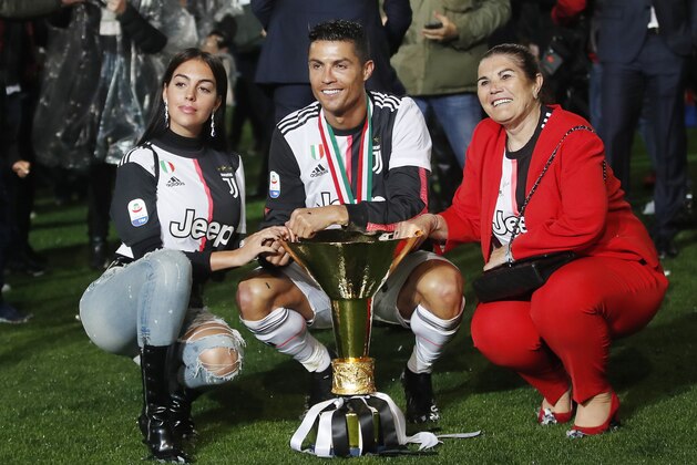 Juventus' Cristiano Ronaldo, center, is flanked by his girlfriend Georgina, left, and his mother Dolores Aveiro, right, pose with the Serie A soccer title trophy, at the Allianz Stadium, in Turin, Italy, Wednesday, April 3, 2019. (AP Photo/Antonio Calanni)