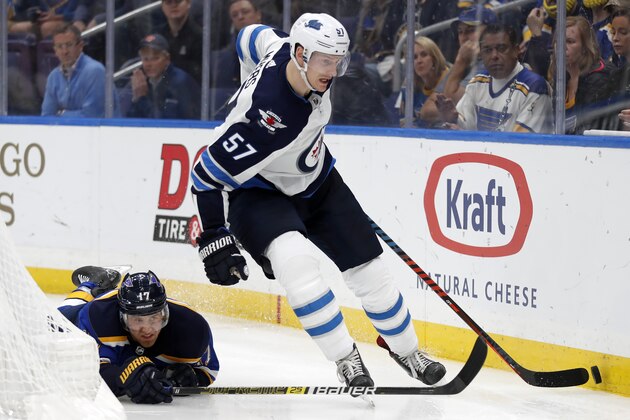 Winnipeg Jets defenseman Tyler Myers (57) moves the puck past the reach of St. Louis Blues left wing Jaden Schwartz (17) during overtime in Game 4 of an NHL first-round hockey playoff series Tuesday, April 16, 2019, in St. Louis. (AP Photo/Jeff Roberson)