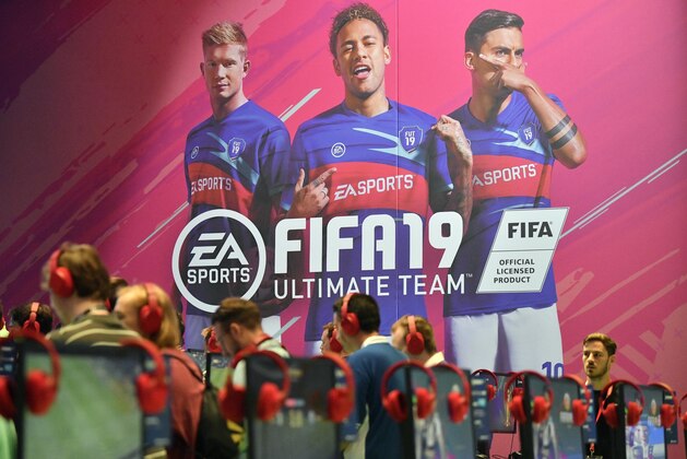 Visitors try out the latest FIFA 19 video game, promoted by a banner with soccer star Neymar, center, at the Gamescom fair for computer games in Cologne, Germany, Tuesday, Aug. 21, 2018. Hundreds of thousands gamers visit the leading European trade fair for digital gaming culture as the meeting point for global companies from the entertainment industry and the international gaming community. (AP Photo/Martin Meissner)