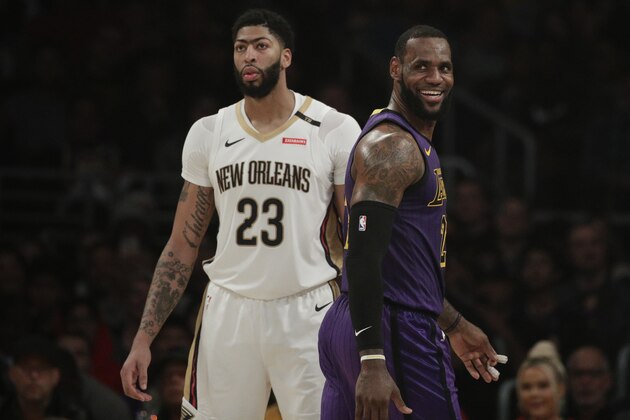 Los Angeles Lakers' LeBron James, right, smiles as he walks past New Orleans Pelicans' Anthony Davis during the first half of an NBA basketball game, Friday, Dec. 21, 2018, in Los Angeles. (AP Photo/Jae C. Hong)