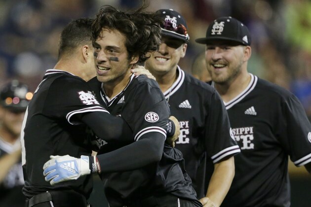 Mississippi State's Marshall Gilbert, second from left, is hugged by teammates after he drove in the winning run against Auburn in the ninth inning of an NCAA College World Series baseball game in Omaha, Neb., Sunday, June 16, 2019. Mississippi State won 5-4. (AP Photo/Nati Harnik)