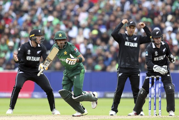 Pakistan's batsman Babar Azam, second from left, makes a run after playing a shot as New Zealand's wicketkeeper Tom Latham, far right, with teammates react during the Cricket World Cup match between New Zealand and Pakistan at the Edgbaston Stadium in Birmingham, England, Wednesday, June 26, 2019. (AP Photo/Rui Vieira)