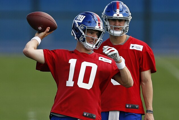 New York Giants quarterback Eli Manning passes in front of quarterback Daniel Jones during an NFL football practice Monday, May 20, 2019, in East Rutherford, N.J. (AP Photo/Adam Hunger)