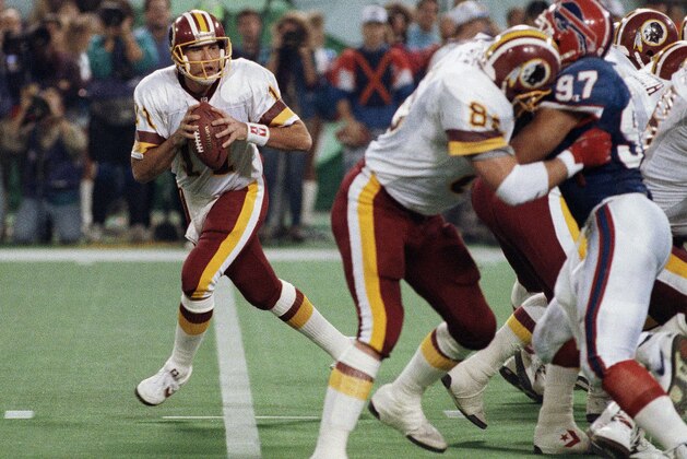 FILE - In this Jan. 26, 1992, file photo, Washington Redskins quarterback Mark Rypien, left, drops to pass during NFL football's Super Bowl XXVI in Minneapolis. Rypien has been arrested in Washington state on suspicion of domestic violence. The Spokesman-Review cites Spokane police saying Rypien was facing a charge of fourth-degree assault. Rypien, 56, was processed at the Spokane County Jail at around 6:30 p.m. Sunday and was awaiting a court appearance Monday, July 1, 2019. (AP Photo/Jim Mone, File)