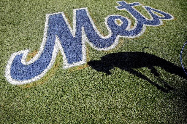 A worker paints a logo on the grass at Citi Field before Game 1 of the National League baseball championship series between the New York Mets and the Chicago Cubs Saturday, Oct. 17, 2015, in New York. (AP Photo/David Goldman)