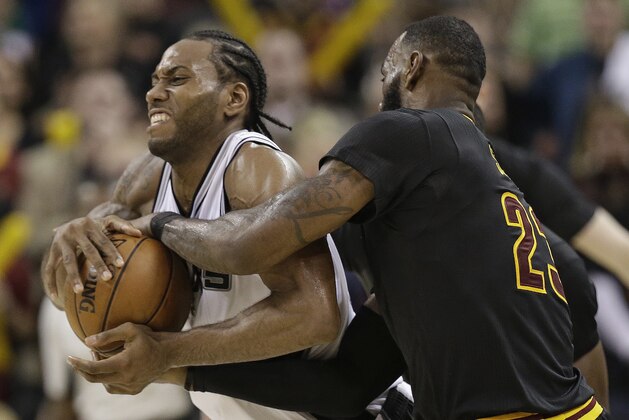 San Antonio Spurs' Kawhi Leonard, left, and Cleveland Cavaliers' LeBron James brab the ball which resulted in a jump ball in overtime in an NBA basketball game, Saturday, Jan. 21, 2017, in Cleveland. (AP Photo/Tony Dejak)