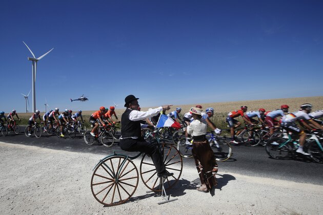 A spectator dressed as cyclist from the olden days watch the pack riding during the fourth stage of the Tour de France cycling race over 214 kilometers (133 miles) with start in Reims and finish in Nancy, France, Tuesday, July 9, 2019. (AP Photo/Christophe Ena)
