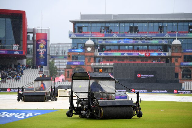 MANCHESTER, ENGLAND - JULY 09:  The ground staff work to keep the pitch dry as play is delayed due to rain during the Semi-Final match of the ICC Cricket World Cup 2019 between India and New Zealand at Old Trafford on July 09, 2019 in Manchester, England. (Photo by Clive Mason/Getty Images)