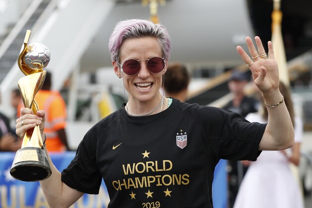 Megan Rapinoe holds the Women's World Cup trophy mafter she and other embers of the U.S. soccer team, winners of a fourth Women's World Cup, arrived at Newark Liberty International Airport, Monday, July 8, 2019, in Newark, N.J. (AP Photo/Kathy Willens)