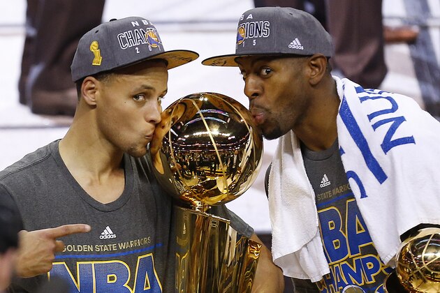 FILE - In this June 17, 2015, file photo, Golden State Warriors Stephen Curry, left, and Andre Iguodala kiss with the Larry O'Brien Trophy after defeating the Cleveland Cavaliers 105-7 in Game 6 of basketball's NBA Finals in Cleveland. NBA players James Harden and Anthony Davis checked right away to see their rating in a video game. Soon enough they can see how their teams rate in the NBA's Western Conference, where Stephen Curry's Golden State Warriors are the champs.  (AP Photo/Paul Sancya, File)