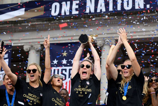 TOPSHOT - USA women's soccer player Lindsey Horan, Megan Rapinoe (C), Alexandra Long(R) and other team members celebrate with the trophy in front of the City Hall after the ticker tape parade for the women's World Cup champions on July 10, 2019 in New York. - Tens of thousands of fans are poised to pack the streets of New York on Wednesday to salute the World Cup-winning US women's team in a ticker-tape parade. Four years after roaring fans lined the route of Lower Manhattan's fabled