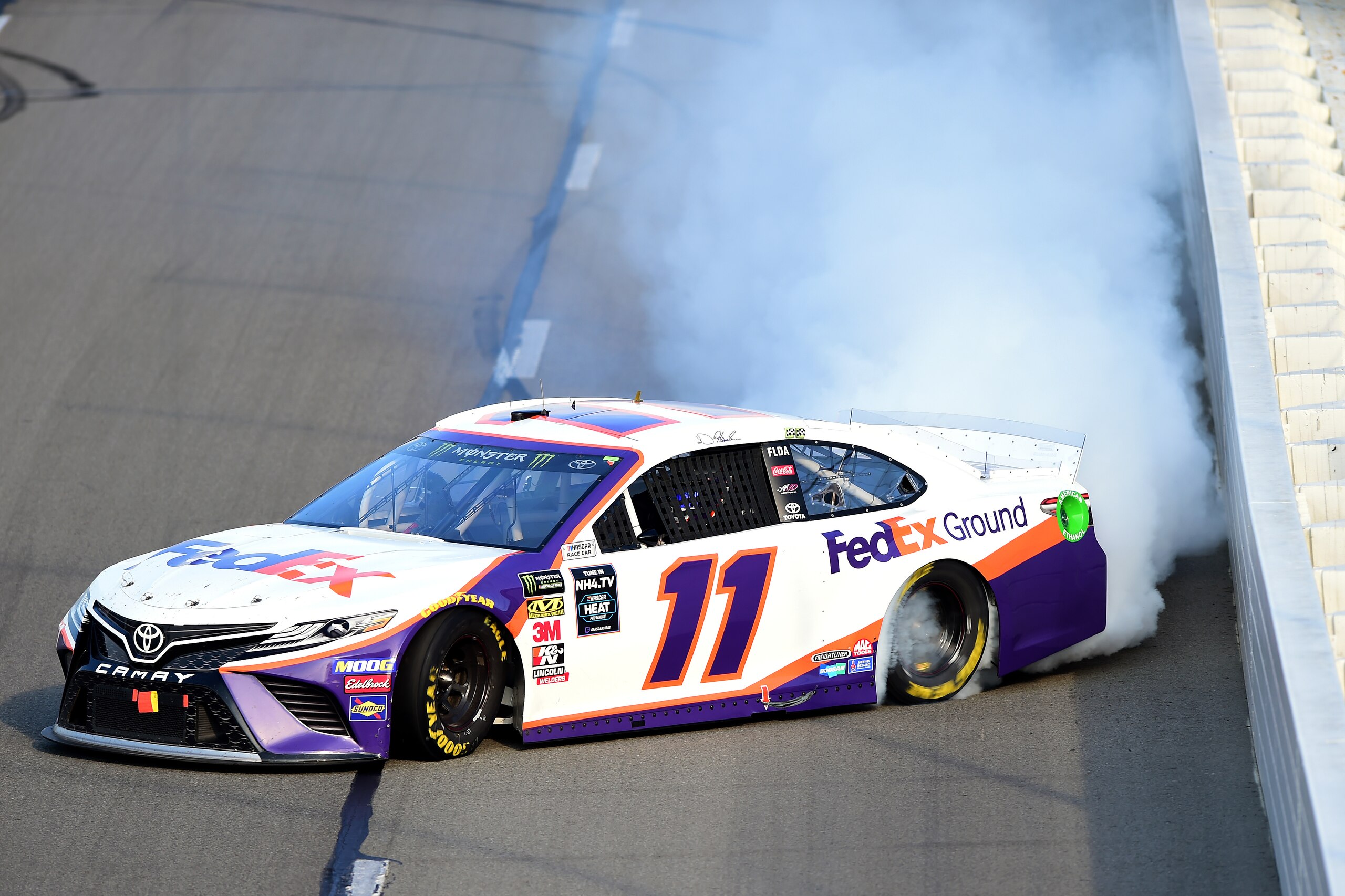 LONG POND, PENNSYLVANIA - JULY 28: Denny Hamlin, driver of the #11 FedEx Ground Toyota, celebrates with a burnout after winning the Monster Energy NASCAR Cup Series Gander RV 400 at Pocono Raceway on July 28, 2019 in Long Pond, Pennsylvania. (Photo by Jared C. Tilton/Getty Images)