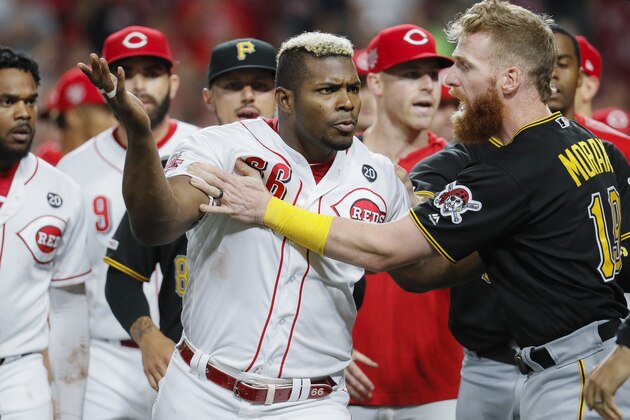 Cincinnati Reds' Yasiel Puig (66) is restrains by Pittsburgh Pirates third baseman Colin Moran (19) during the ninth inning of a baseball game Tuesday, July 30, 2019, in Cincinnati. (AP Photo/John Minchillo)