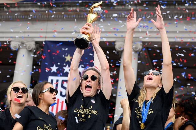 USA women's soccer player Lindsey Horan(L)Megan Rapinoe (C), Alexandra Long(R) and other team members celebrate with the trophy in front of the City Hall after the ticker tape parade for the women's World Cup champions on July 10, 2019 in New York. - Tens of thousands of fans are poised to pack the streets of New York on Wednesday to salute the World Cup-winning US women's team in a ticker-tape parade. Four years after roaring fans lined the route of Lower Manhattan's fabled