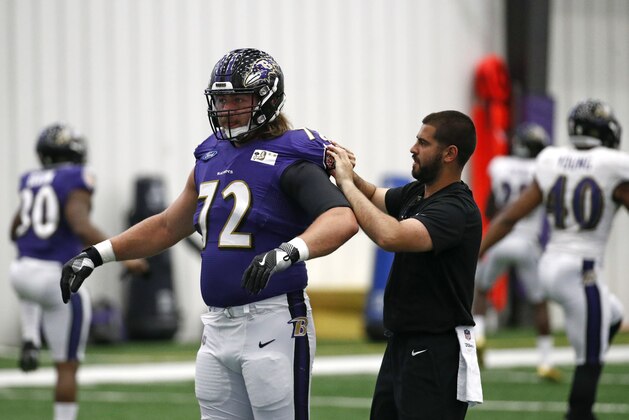 A member of the Baltimore Ravens adjusts offensive tackle Alex Lewis' jersey during an NFL football training camp practice at the team's headquarters, Tuesday, July 24, 2018, in Owings Mills, Md. (AP Photo/Patrick Semansky)