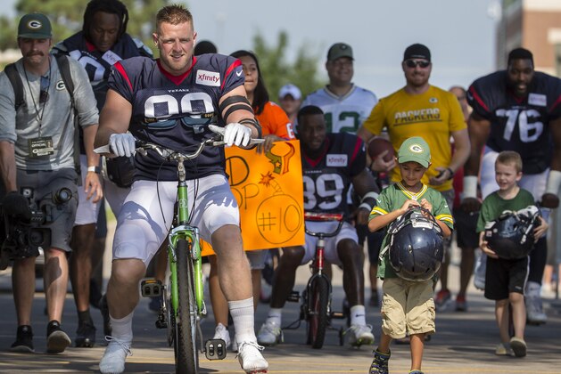 Houston Texans' J.J. Watt rides a bike to a joint NFL football practice between the Texans and the Green Bay Packers Monday, Aug 5, 2019, in Green Bay, Wis. (AP Photo/Mike Roemer)