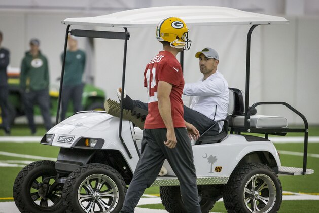 FILE - In this June 12, 2019, file photo, quarterback Aaron Rodgers, left, walks past head coach Matt LaFleur during an NFL football practice in Green Bay, Wisc. LeFleur is recovering from a torn Achilles. LaFleur opens his first training camp as Packers head coach with his biggest issue being the nagging Achilles injury. LaFleur said Wednesday, July 24, 2019, that he hopes to be out of his walking boot in the next couple weeks as he continues to recover from a ruptured Achilles tendon he suffered in May. As for his on-field concerns and relationship with quarterback Aaron Rodgers, Lafleur says he enjoys the challenge of coaching Rodgers and called the two-time NFL MVP one of the most competitive players he’s ever been around. (AP Photo/Mike Roemer, File)