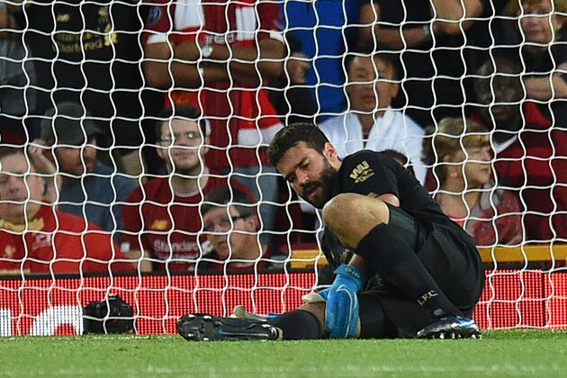 Liverpool's Brazilian goalkeeper Alisson Becker waits to receive medical attention during the English Premier League football match between Liverpool and Norwich City at Anfield in Liverpool, north west England on August 9, 2019. (Photo by Oli SCARFF / AFP) / RESTRICTED TO EDITORIAL USE. No use with unauthorized audio, video, data, fixture lists, club/league logos or 'live' services. Online in-match use limited to 120 images. An additional 40 images may be used in extra time. No video emulation. Social media in-match use limited to 120 images. An additional 40 images may be used in extra time. No use in betting publications, games or single club/league/player publications. /         (Photo credit should read OLI SCARFF/AFP/Getty Images)