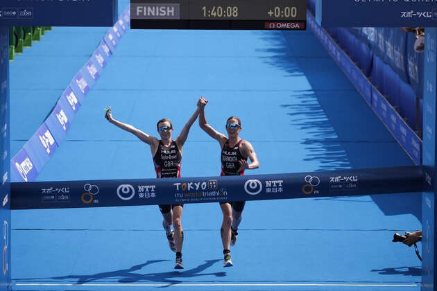 Britain's Georgia Taylor-Brown, left, and Jessica Learmonth hold hands as they cross the finish line during a women's triathlon test event at Odaiba Marine Park, a venue for marathon swimming and triathlon at the Tokyo 2020 Olympics, Thursday, Aug. 15, 2019, in Tokyo. (AP Photo/Jae C. Hong)