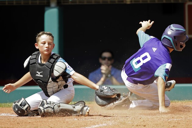 Italy's Davide Lugli (8) slides past the tag of Salem, Oregon's Riley Wilson (1) scoring during the fifth inning of a baseball game at the Little League World Series tournament in South Williamsport, Pa., Tuesday, Aug. 20, 2019. Salem, Oregon won the game 4-3. (AP Photo/Tom E. Puskar)