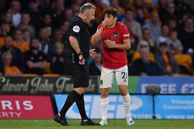 English referee Jonathan Moss (L) shows a yellow card to Manchester United's Welsh midfielder Daniel James during the English Premier League football match between Wolverhampton Wanderers and Manchester United at the Molineux stadium in Wolverhampton, central England  on August 19, 2019. (Photo by Paul ELLIS / AFP) / RESTRICTED TO EDITORIAL USE. No use with unauthorized audio, video, data, fixture lists, club/league logos or 'live' services. Online in-match use limited to 120 images. An additional 40 images may be used in extra time. No video emulation. Social media in-match use limited to 120 images. An additional 40 images may be used in extra time. No use in betting publications, games or single club/league/player publications. /         (Photo credit should read PAUL ELLIS/AFP/Getty Images)
