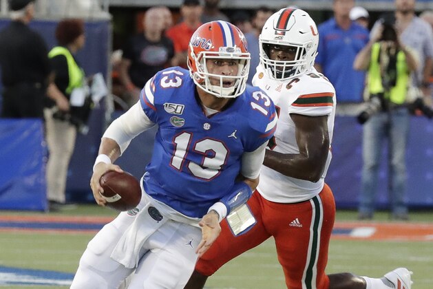 Florida quarterback Feleipe Franks (13) scrambles as he is pressured by Miami linebacker Shaquille Quarterman, right, during the first half of an NCAA college football game Saturday, Aug. 24, 2019, in Orlando, Fla. (AP Photo/John Raoux)