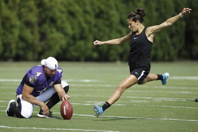 Baltimore Ravens' Sam Koch holds the ball for United States soccer player Carli Lloyd as she attempts to kick a field goal after the Philadelphia Eagles and the Baltimore Ravens held a joint NFL football practice in Philadelphia, Tuesday, Aug. 20, 2019. (AP Photo/Matt Rourke)