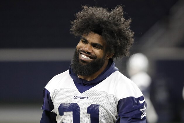 Dallas Cowboys running back Ezekiel Elliott smiles as he walks off the field after participating in drills at the team's NFL football training facility in Frisco, Texas, Wednesday, June 12, 2019. (AP Photo/Tony Gutierrez