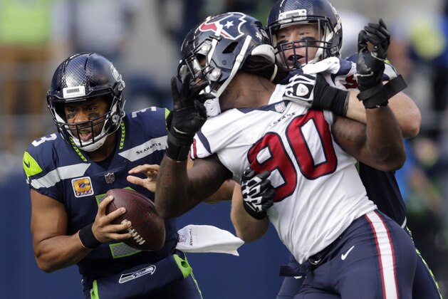 Seattle Seahawks quarterback Russell Wilson, left, keeps the ball as Seattle Seahawks offensive guard Ethan Pocic, right, tries to block Houston Texans outside linebacker Jadeveon Clowney (90) in the second half of an NFL football game, Sunday, Oct. 29, 2017, in Seattle. (AP Photo/Stephen Brashear)