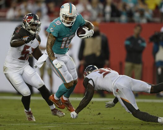 Miami Dolphins wide receiver Kenny Stills (10) slips between Tampa Bay Buccaneers defensive end Noah Spence (57) and free safety Jordan Whitehead (31) during the first half of an NFL preseason football game Friday, Aug. 16, 2019, in Tampa, Fla. (AP Photo/Jason Behnken)