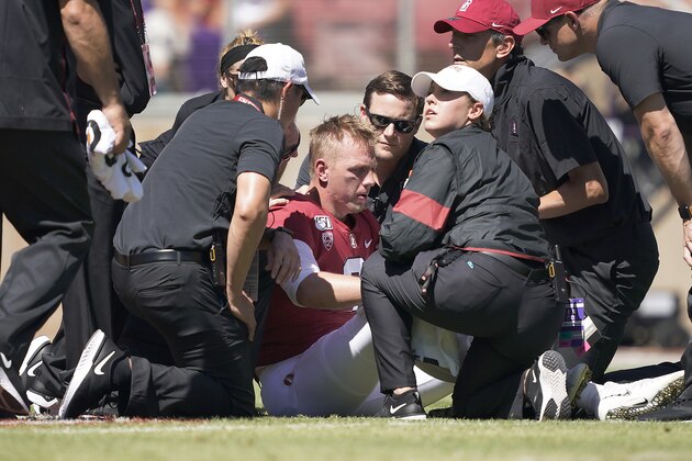 Stanford quarterback K.J. Costello, center, sits on the ground as trainers tend to him during the first half of an NCAA college football game against Northwestern on Saturday, Aug. 31, 2019, in Stanford, Calif. K.J. Costello was taken out of the game. (AP Photo/Tony Avelar)