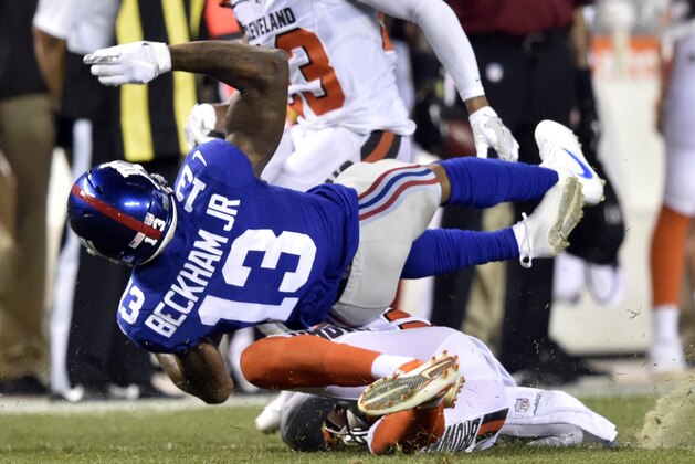 El wide receiver de los Giants, Odell Beckham Jr., arriba, es derribado en un partido de pretemporada contra los Browns de Cleveland el lunes, 21 de agosto de 2017, en Cleveland. (AP Foto/David Ric)