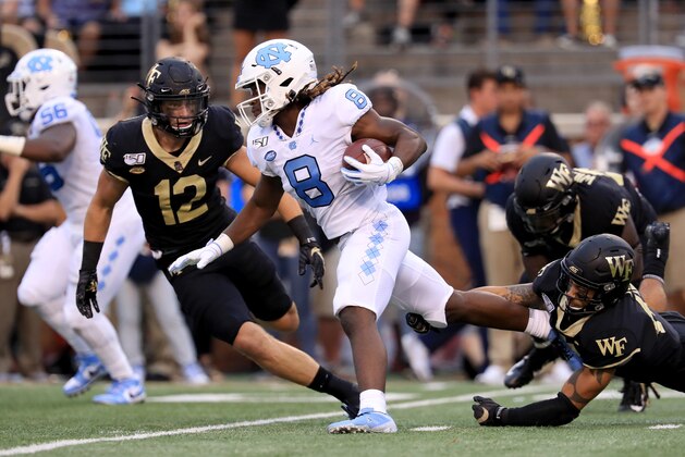 WINSTON SALEM, NORTH CAROLINA - SEPTEMBER 13: Jamie Newman #12 of the Wake Forest Demon Deacons tries to stop Michael Carter #8 of the North Carolina Tar Heels during their game at BB&T Field on September 13, 2019 in Winston Salem, North Carolina. (Photo by Streeter Lecka/Getty Images)