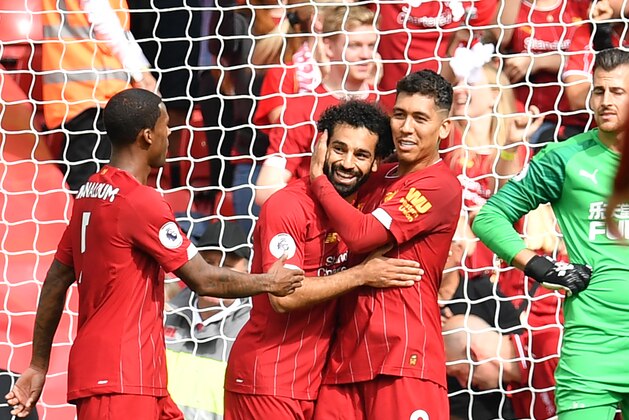 Liverpool's Egyptian midfielder Mohamed Salah (CL) celebrates with Liverpool's Brazilian midfielder Roberto Firmino (R) after scoring the team's third goal during the English Premier League football match between Liverpool and Newcastle at Anfield in Liverpool, north west England on September 14, 2019. (Photo by Paul ELLIS / AFP) / RESTRICTED TO EDITORIAL USE. No use with unauthorized audio, video, data, fixture lists, club/league logos or 'live' services. Online in-match use limited to 120 images. An additional 40 images may be used in extra time. No video emulation. Social media in-match use limited to 120 images. An additional 40 images may be used in extra time. No use in betting publications, games or single club/league/player publications. /         (Photo credit should read PAUL ELLIS/AFP/Getty Images)