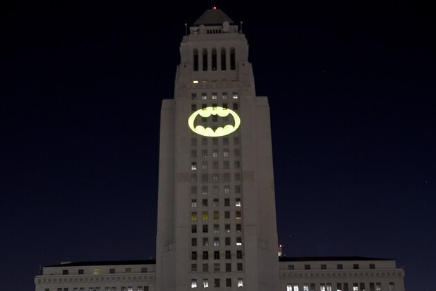 Fans gather as a Bat-Signal is projected onto City Hall during a tribute to Fans gather as a Bat-Signal is projected onto City Hall during a tribute to