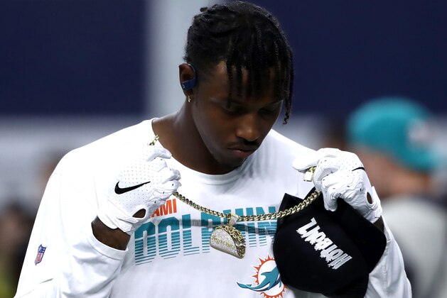 ARLINGTON, TEXAS - SEPTEMBER 22: Taco Charlton #96 of the Miami Dolphins takes off his chain while holding a ARLINGTON, TEXAS - SEPTEMBER 22: Taco Charlton #96 of the Miami Dolphins takes off his chain while holding a