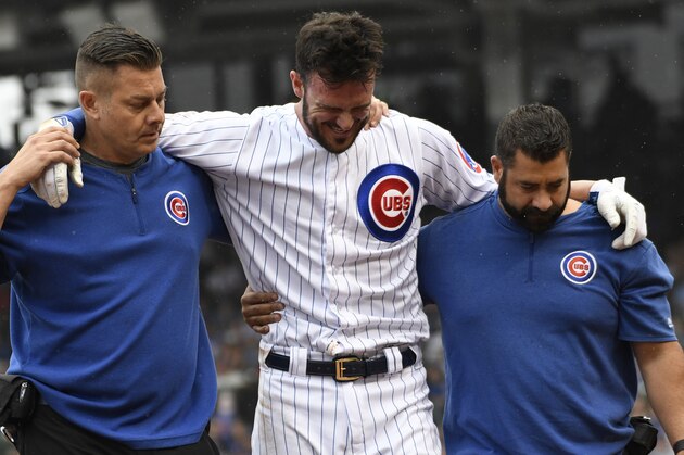 CHICAGO, ILLINOIS - SEPTEMBER 22: Kris Bryant #17 of the Chicago Cubs is helped off the field by trainers after hurting him self running to first base against the St. Louis Cardinals during the third inning at Wrigley Field on September 22, 2019 in Chicago, Illinois. (Photo by David Banks/Getty Images)