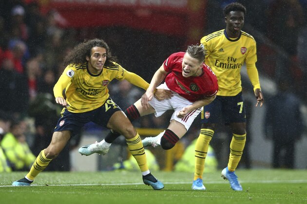 Manchester United's Scott McTominay, centre, vies for the ball with Arsenal's Matteo Guendouzi, left, during the English Premier League soccer match between Manchester United and Arsenal at Old Trafford in Manchester, England, Monday, Sept. 30, 2019. (AP Photo/Dave Thompson)